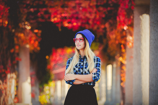 Young white style girl in red glasses and shirt in a red grapes alley. Autumn season