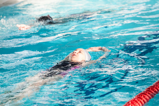 Young children swimming backstroke in pool at lane