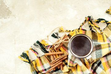 Autumn composition. Cup of coffee, blanket, autumn leaves, cinnamon sticks on beige background. Flat lay, top view.