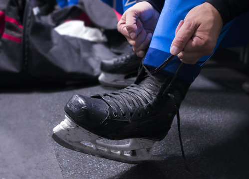 hands tying shoelaces of ice hockey skates in locker room