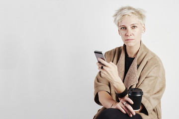 Portrait of blond caucasian woman with short hair drinks takeaway coffee, white background.Package design template mockup.