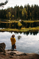 Woman in a yellow poncho and hat in the autumn time in national park Nuuksio, Finland