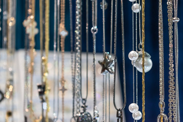 Stylish beautiful bijouterie hanging on the stand in the accessories store. Various Jewelry bijouterie show in retail shop window display showcase