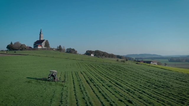Traktor auf Feld beim Gras wenden - Luftbild