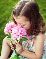 Pretty cute child holding and sniffing flowers