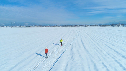 AERIAL: Unrecognizable active women skiing cross country on a sunny winter day.