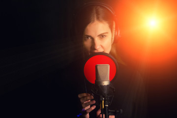 Singing girl sing to the professional microphone in the record studio. Process of create a new hit...