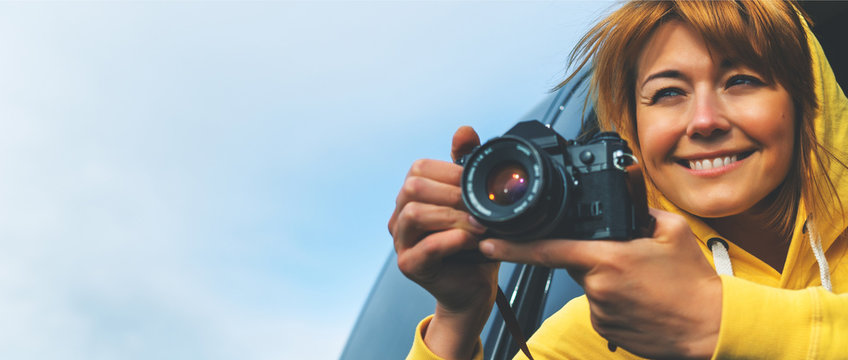 smile tourist girl in an open window of a auto car taking photography click on retro vintage photo camera, photographer looking on camera technology, blogger using hobby content concept, enjoy trip