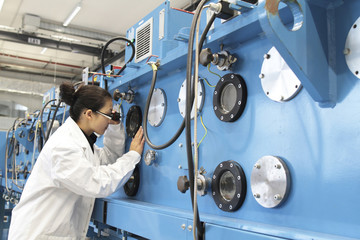 Junge Technikerin mit Kittel arbeitet in einem technischen Labor