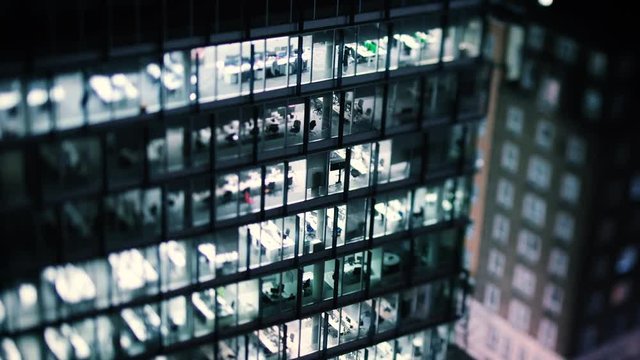 Cinematic footage - aerial helicopter view to skyscraper building in banking business district in worldwide hub with working late light offices - slow focusing with a tilt-shift lens - 4K UHD video