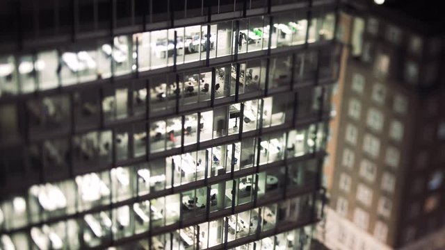 Aerial helicopter view to skyscraper building in banking business district in worldwide hub with working late light offices - slow focusing with a tilt-shift lens in cinematic  color cast - 4K UHD vid