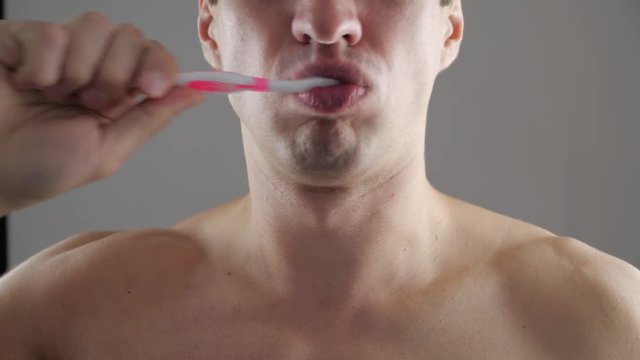 Young man brushes his teeth and suddenly feels a strong toothache. Dental problems.