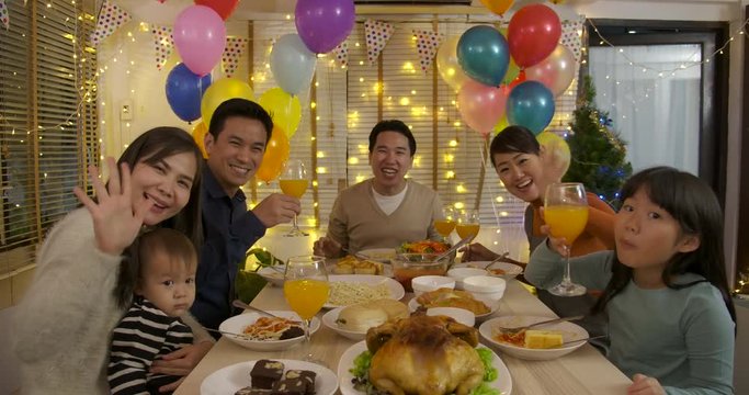 Happy Asian family making video call and enjoying christmas dinner together at home.