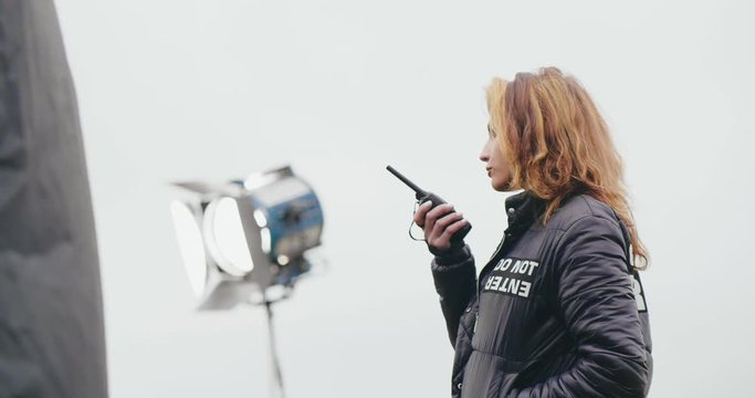 Female co-director giving instructions using two way radio.