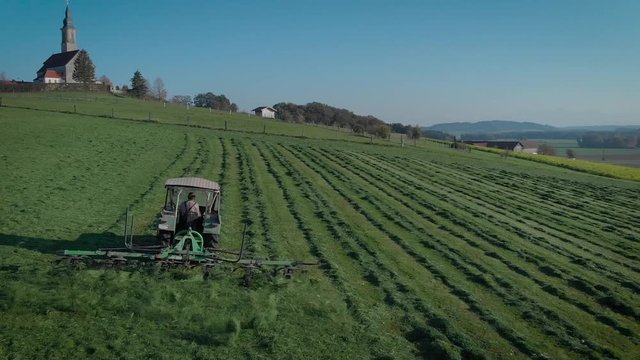 Traktor auf Feld beim Gras wenden - Luftbild