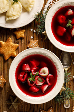 Christmas beetroot soup, borscht with small dumplings with mushroom filling in a ceramic bowl on a wooden table, top view.  Traditional Christmas eve dish in Poland. 