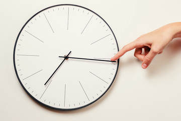 Woman hand stop time on a round clock, time management and deadline concept
