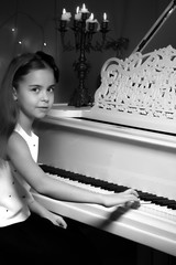 Little girl plays the piano by candlelight.