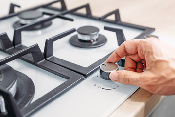 Man's hand set temperature on control panel of hob