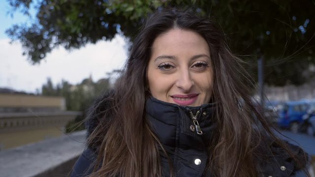 Smiling relaxed cute brunette looking at camera- windy day- slow motion