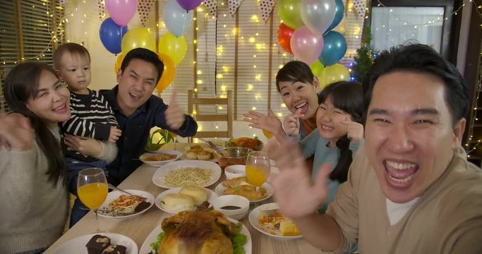 Happy Asian family taking selfie photo at a Party. Happy friends enjoying christmas dinner together at home.