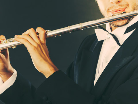 Elegantly dressed male musician playing flute