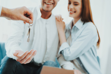 Obraz premium Young Couple Stare On The Key In Rieltors Hands.