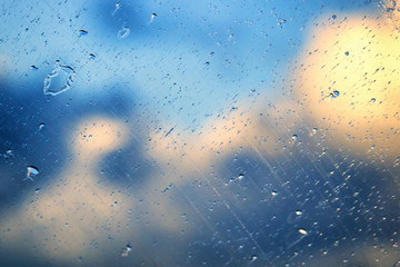 Beautiful drops on a glass against a blue sky with sun and clouds. Clear glass
