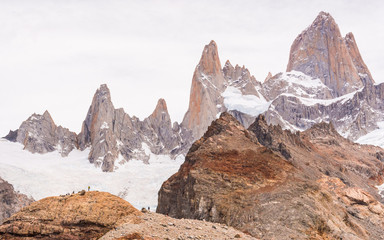 Far away abstract view to Fitz Roy mountain range with tiny people and tourists walking in the sorroundings by the incredible glaciers and peaks