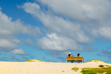 Two girls sitting on a bank in the beach