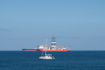 sailing boat, drilling ship and tanker on ocean horizon  