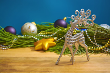 Beautiful silver reindeer toy next to fir branch.