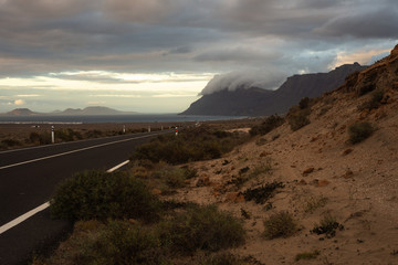 Obraz premium the road to the ocean descends from the hills of the desert and the mountain wrapped in clouds