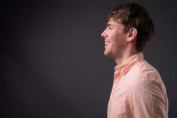 Portrait of young handsome businessman against gray background