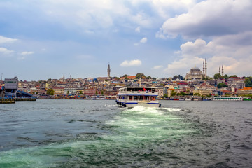Obraz premium Touristic landmarks from sea voyage on Bosphorus. Cityscape of Istanbul at sunset - old mosque and turkish steamboats, view on Golden Horn.