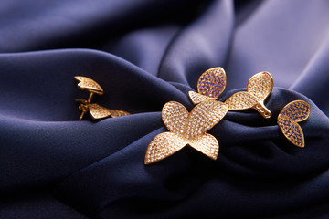 Beautiful gold ring and earrings with precious gemstone stones on blue silk background with copy...