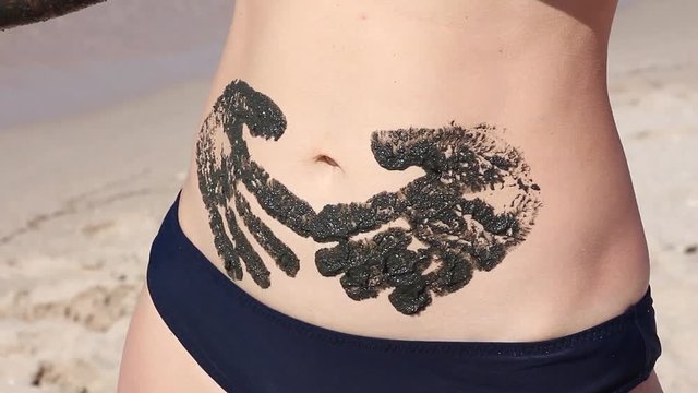 the girl leaves handprints on her stomach with therapeutic mud