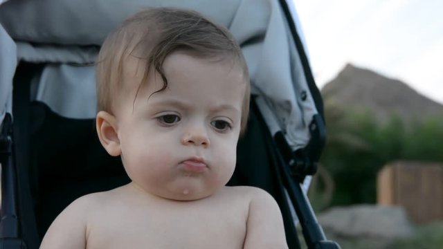 Child  in stroller sitting on a beach near the sea