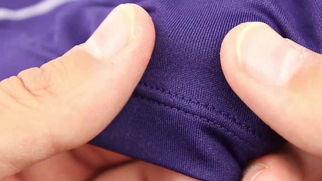 human hand testing purple synthetic thermal underwear, closeup(macro), the tensile test