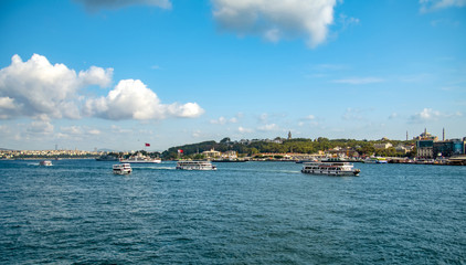 Fototapeta premium Touristic landmarks from sea voyage on Bosphorus. Cityscape of Istanbul at sunset - old mosque and turkish steamboats, view on Golden Horn.