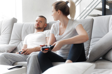 Young couple playing TV console on sofa