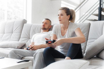 Young couple playing TV console on sofa