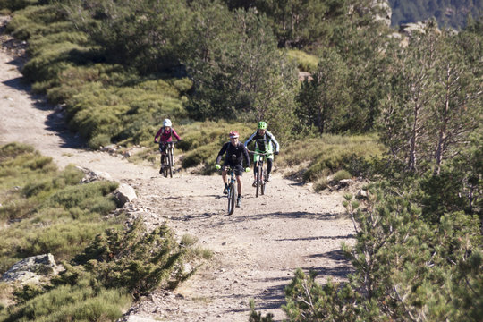 Women and mountain biking man riding on bikes in the mountains forest landscape. MTB track cycling couple enduro flow trail. Outdoor sports activity. Hard and steep climb