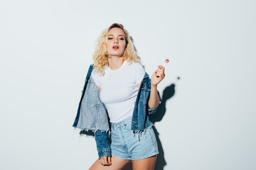 Portrait of a cute young woman wearing glasses and biting a lollipop isolated on white background