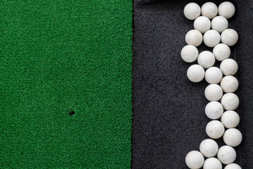 Golf balls on a synthetic grass mat at a practice range.