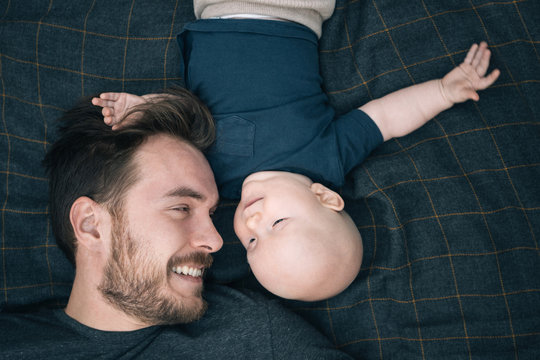 Happy father and his baby son top view. Family portrait from above with 5-months child lying in park. Looking at each other, having fun, sharing moment.  Father's Day concept