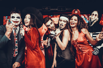 Young People in Halloween Costumes Singing Karaoke