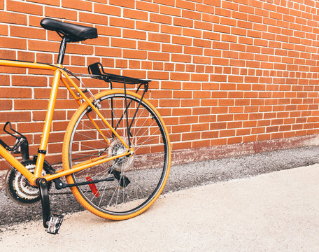 Orange bicycle near red brick wall with copy space