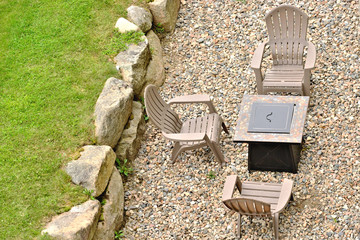 Three chairs and a fire pit along a stone wall