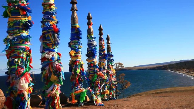 Lake Baikal. Olkhon Island. Village Khuzhir. Sacred place on cape Burkhan. Colored ribbons of desires and the prayer flags in the wind against a blue sky and the Saraisky Gulf